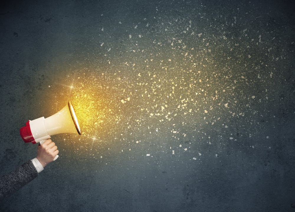 Caucasian business hand holding megaphone with yellow sparkles