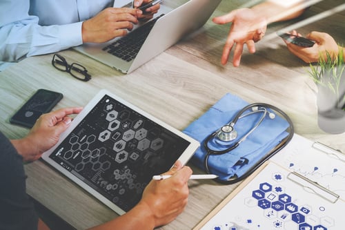 top view of Medicine doctor hand working with modern computer and digital pro tablet with his team with digital medical diagram on wooden desk as medical concept