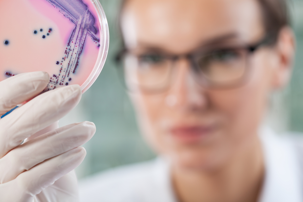 Microbiologist holding a Petri dish with bacteria, horizontal