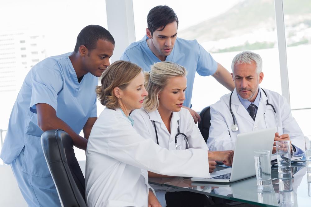 Serious medical team using a laptop in a bright office Serious medical team using a laptop in a bright office